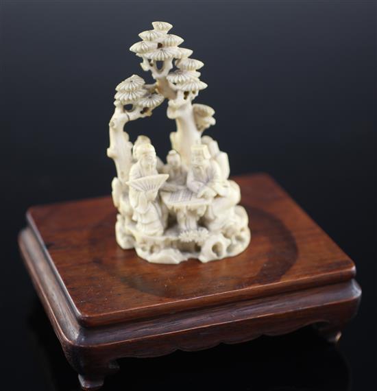 A Chinese ivory group of scholars playing weiqi beneath a pine tree, 19th century, 8.7cm, wood stand, slight repair